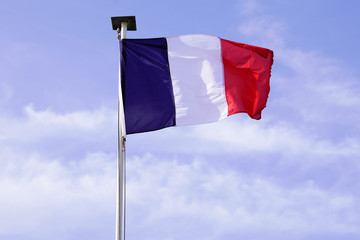 French flag of France waving over a blue cloudy sky