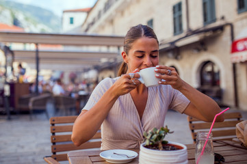 Portrait of happy pretty woman drinking coffee at terrace