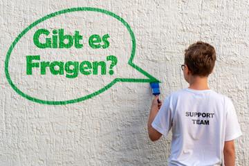 Schüler vor einer Wand mit Sprechblase und der Frage GIBT ES FRAGEN