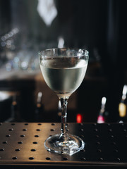 Clear alcohol cocktail in glass on bar counter