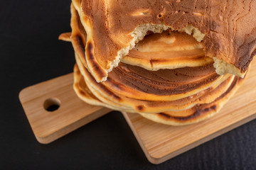 One cake bitten off a stack of other pancakes. Tasty cookies on the kitchen table.