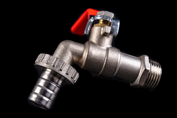 New steel water valve. Plumbing accessories needed for home renovation. Dark background.