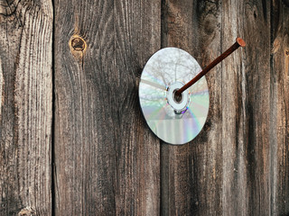 The cd hangs on the nail. Old boards and wood. The texture of the old tree.