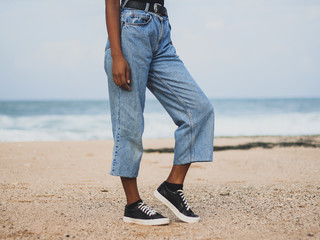 Girl modeling pair of light blue mom jeans and pair of black shoes with white borders and white...