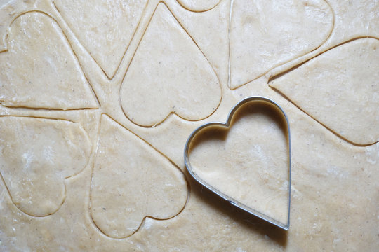 Heart shaped cookie cutters cutting out holiday cookies. - Powered by Adobe
