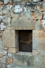 Ventana vieja de casa de pueblo sobre muro de piedra.