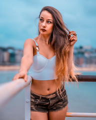 A young brunette with a top in a harbor next to the sea