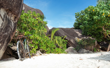 Fototapeta premium Bicycle stood up at beautiful tropical beach with granite rocks. Space for text