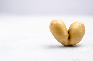 Despicable potatoes in the shape of a heart on a gray background, copy space place