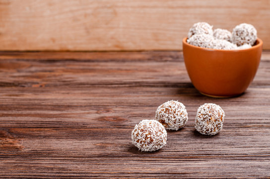 Balls of energy dates, nuts, oats, sprinkled with coconut powder close-up on a wooden background with copy space with place for your text