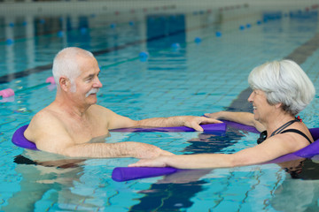 a senior couple is swimming slowly in the swimming pool