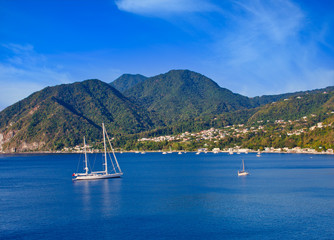 A large white sailboat anchored in a brilliant blue bay