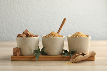 Bowls with different types of brown sugar on wooden table