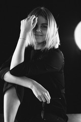 Obraz premium beautiful girl in a black suit sits on a chair and a desk with a laptop