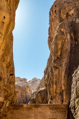 Breathtaking natural gorge called Al-Siq, carved in the red cliffs by the water flow, Petra ancient city complex and tourist attraction, Hashemite Kingdom of Jordan. Sunny winter day, cloudless sky