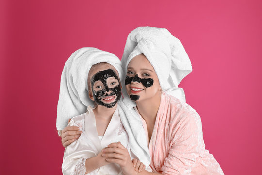 Happy Mother And Daughter With Black Facial Masks On Pink Background