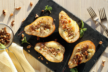 Ready-made dessert of baked pears, dor blue cheese, nuts and honey. Vegetarian pear dessert in a plate on a wooden surface