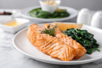 Tasty salmon with spinach and lemon on table