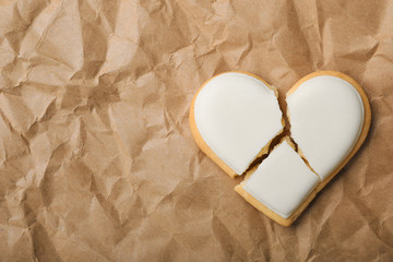 Broken heart shaped cookie on crumpled paper, top view with space for text. Relationship problems...