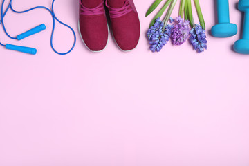 Flat lay composition with spring flowers and sports items on pink background. Space for text