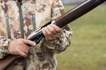 Charges a hunting smooth-bore rifle, hunting a pheasant with dogs. A hunter in camouflage is standing with a weapon.