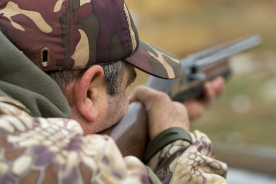 A hunter in camouflage at the shooting range calibrates the weapon. A man shoots at targets.