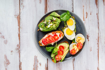 Sweet potato toasts with avocado, boiled eggs, tomatoes and sesame seeds on white rustic background. Healthy meal concept. Clean eating, Pescetarian food, top view