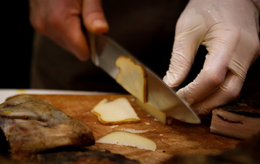 Cutting aged cheese in grocery shop