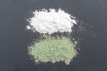 Fototapeta na wymiar Close-up of a cosmetic dry white and green clay powder on gray background.