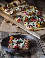 A close up of a plate with a slice of flat bread pizza and more in behind.