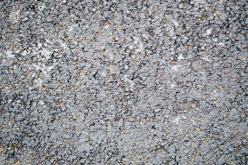 Gray asphalt road with small pebbles and cracks. Texture, background