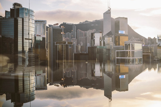 Cityscape with modern skyscrapers reflected in calm sea.,Hong Kong