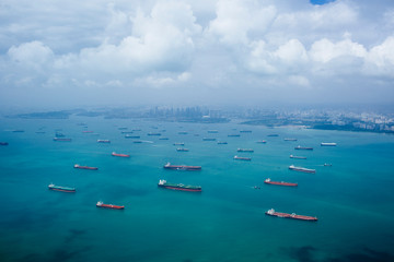 High angle view of barges and cargo ships in a bay, cityscape in the distance.