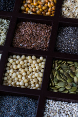 Angled view of a wooden box with compartments of different seeds and grains.