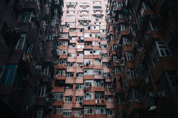 Low angle view of facade of towering residential complex with windows and balconies.,Hong Kong