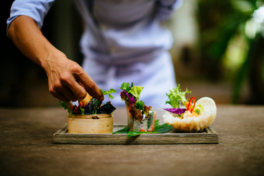 Close up of chef putting the final touches on a dish of salads and spring rolls.,Saigon