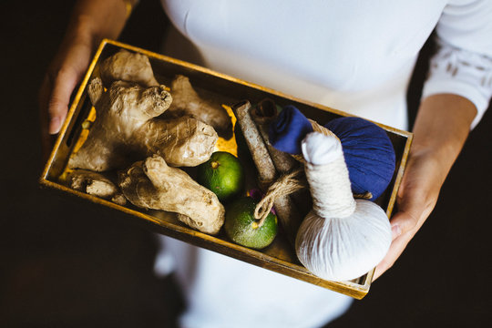 High angle view of person holding tray with fresh ginger and limes and herbal compresses.,Saigon