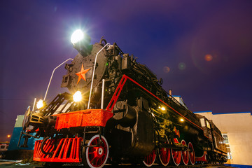 Old black steam locomotive on railway station at night
