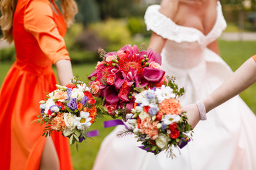 Bride and bridesmaid holding bouquets of flowers in hands.