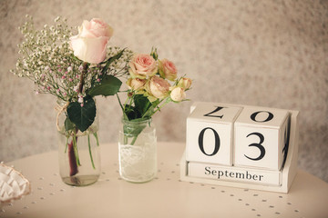 arrangement of bouquets of flowers of roses on the table and wooden cube calendar dated third...