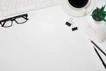 Workspace, White office desk table. View from above of keyboard, computer mouse, pen, pencil, notebooks, eyeglasses, white cup of black coffee. Top view, flat lay with copy space. Business concept.