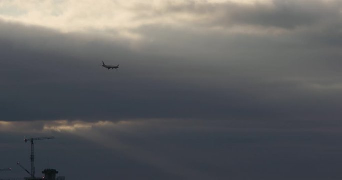 Hounslow, UK - January 10 2020: A regional British Airways jet passes in front of stormy clouds with the sunlight peaking through as it approaches Heathrow Airport