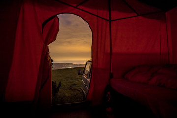Home made retro camper on a van or lorry. View from the tent on a caravan camping towards evening panorama over the hills during the night.