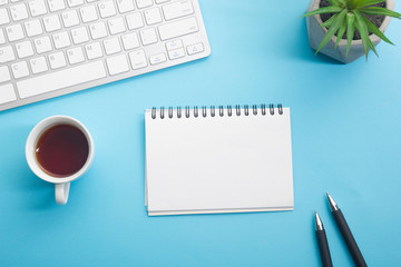 Blue desk office with laptop, smartphone and other work supplies with cup of coffee. Top view with copy space for input the text. Designer workspace on desk table essential elements on flat lay
