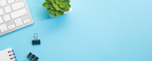 Blue desk office with laptop, smartphone and other work supplies with cup of coffee. Top view with...