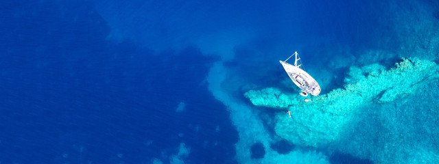 Aerial drone ultra wide photo of sail boat docked in tropical exotic bay with turquoise clear sea