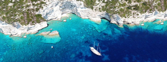 Aerial drone ultra wide photo of breathtaking turquoise exotic bay of blue lagoon in island of Paxos visited by sail boats, Ionian, Greece