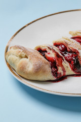 Mixed berry sweet roll on a plate full of frozen raspberries, blueberries and strawberries