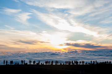 people watching sunset beyond sea of clouds