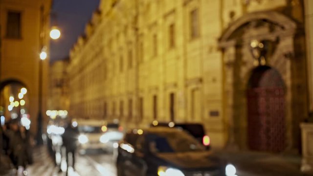 Blurred modern vehicles and crowd of people moving outside old building on city street at night